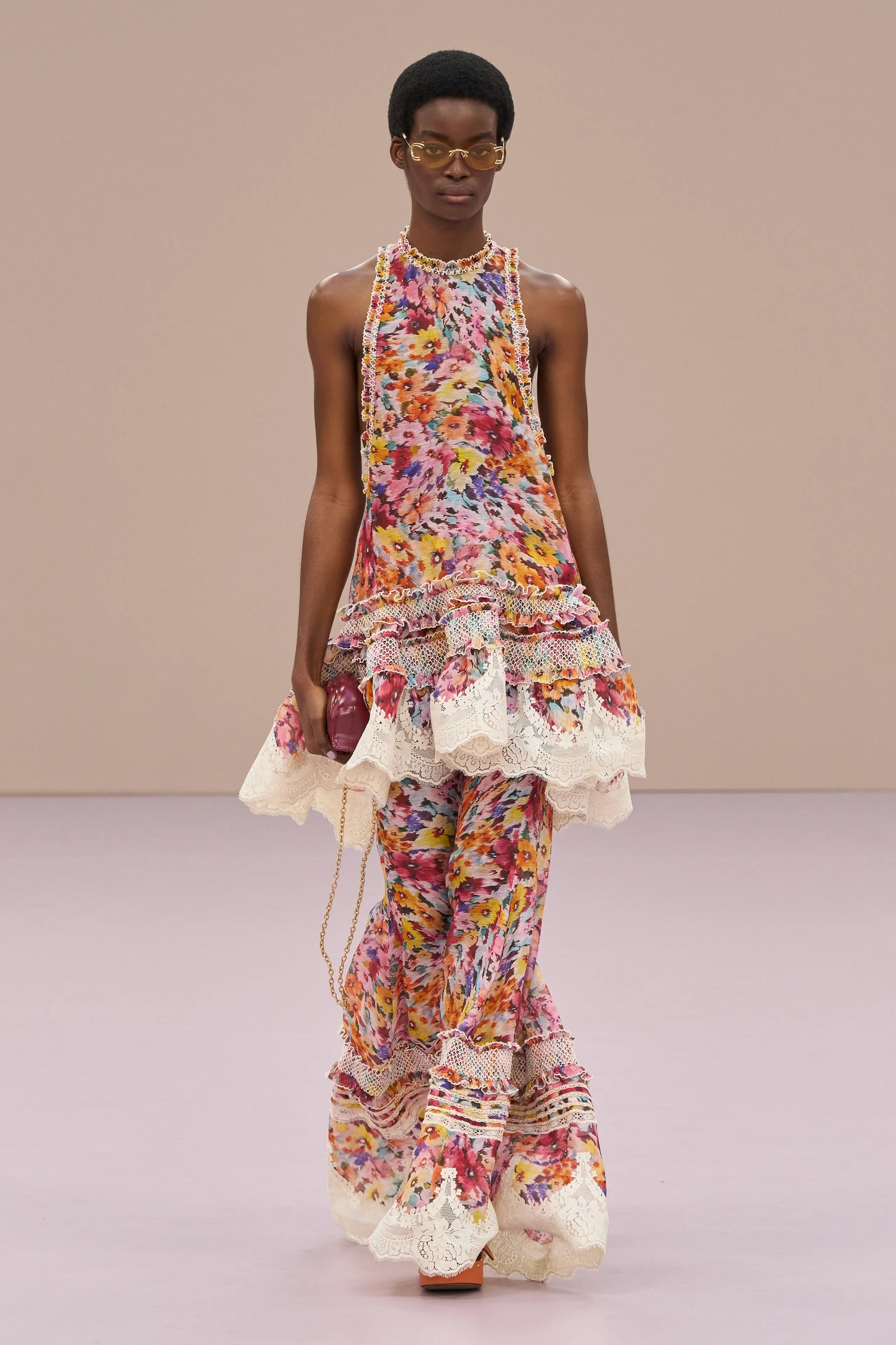 Woman wearing a colorful floral dress with ruffled layers on a beige background