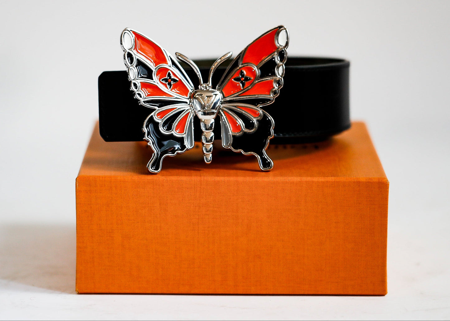 Butterfly-shaped belt buckle on a box with a white background