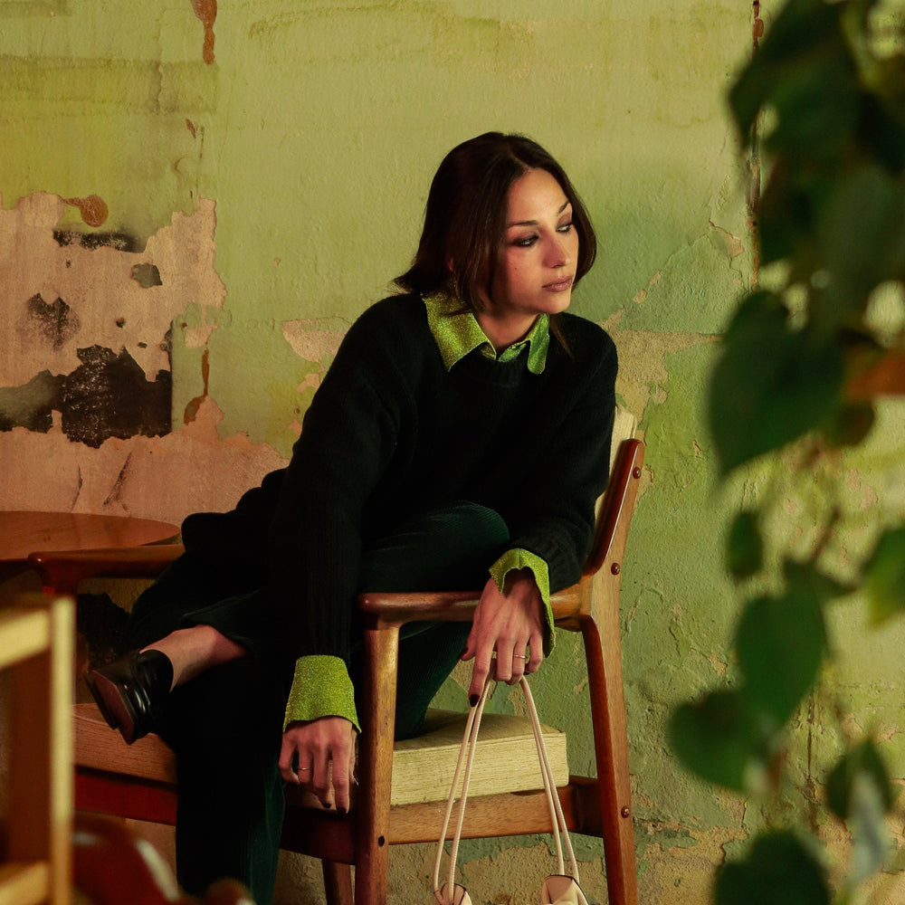 Woman sitting on a chair against a green wall with peeling paint