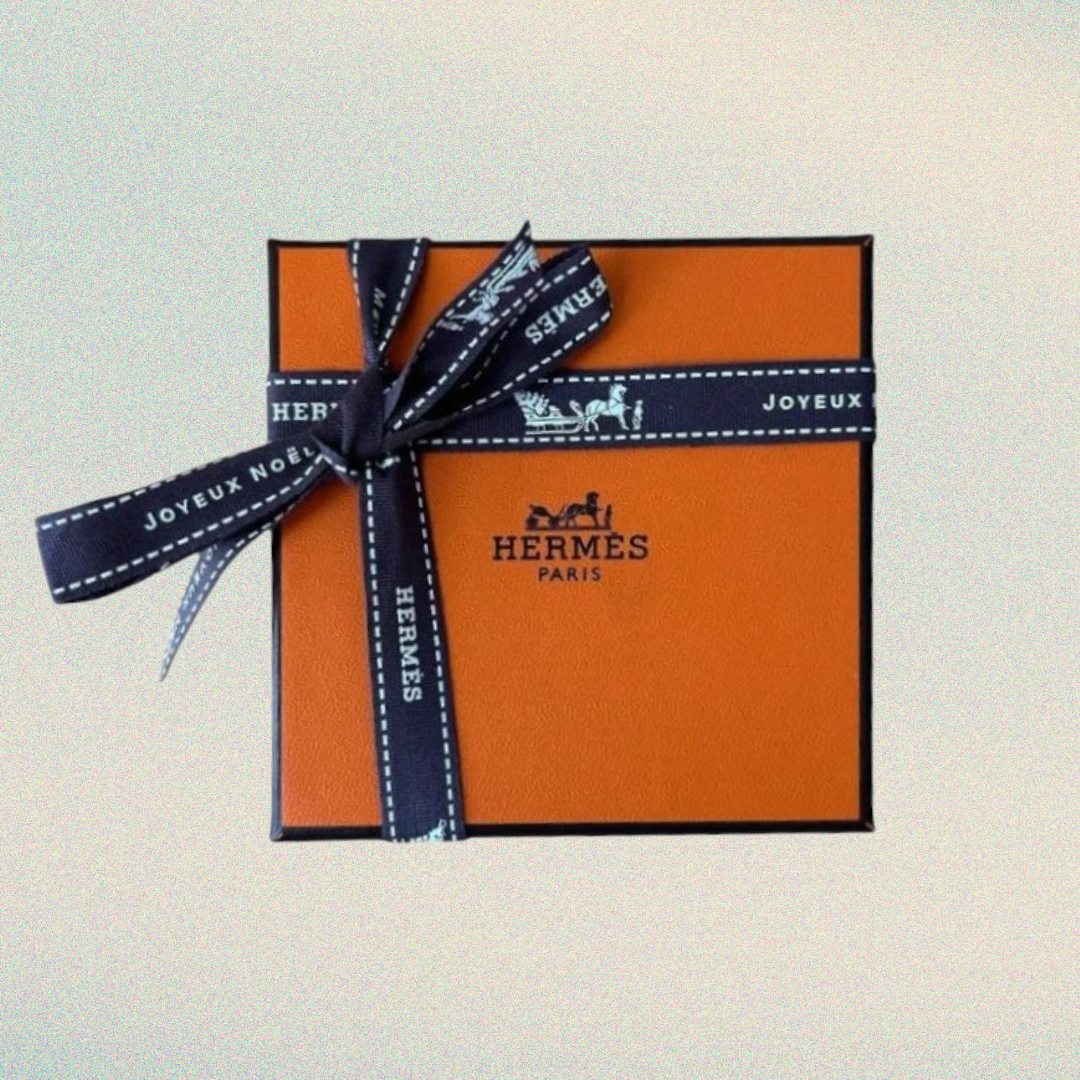 Orange Hermes gift box with a blue ribbon on a light gray background