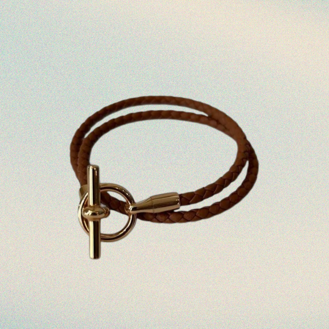 Brown leather bracelet with gold clasp on a light background