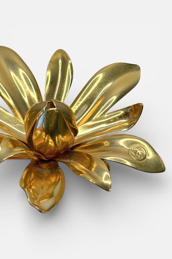 Gold flower-shaped brooch on a white background