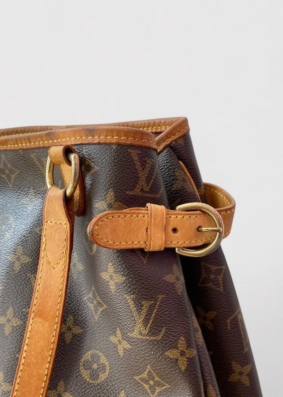 Louis Vuitton handbag with monogram pattern and brown leather strap on a light gray background