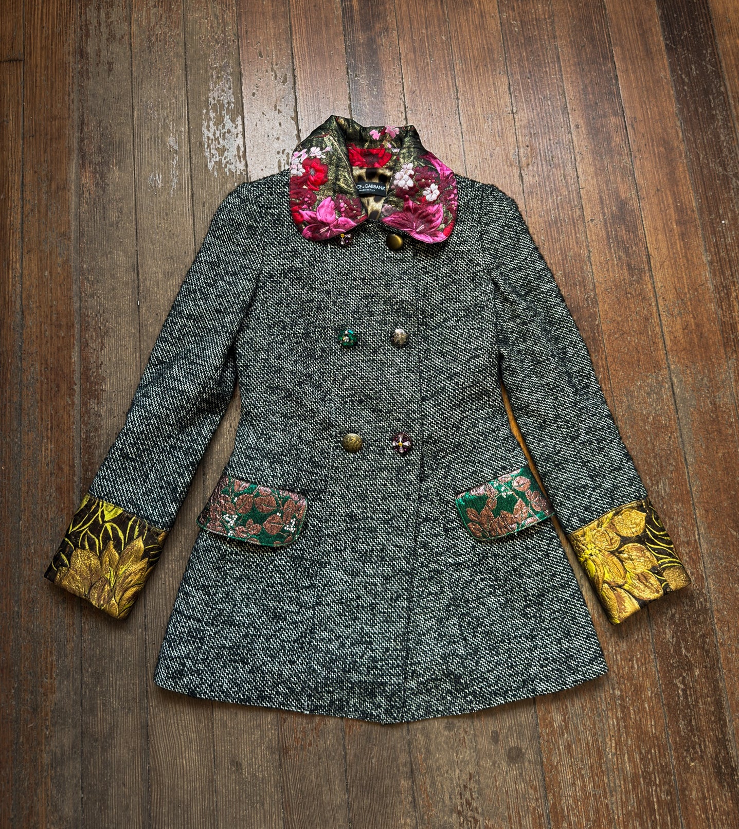 Gray coat with floral and yellow accents on a wooden surface